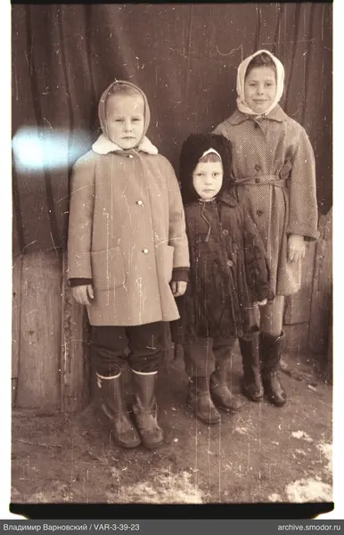 Group portrait of three children by a wooden wall