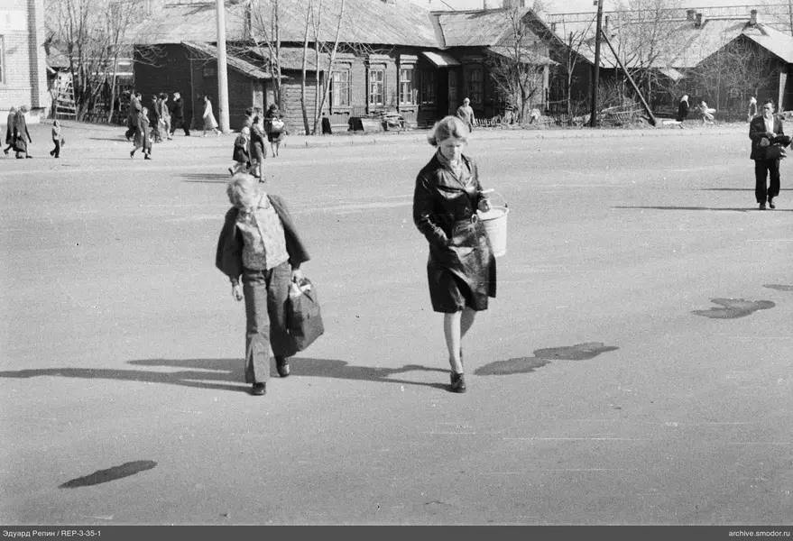 Две женщины на улице с деревянными домами