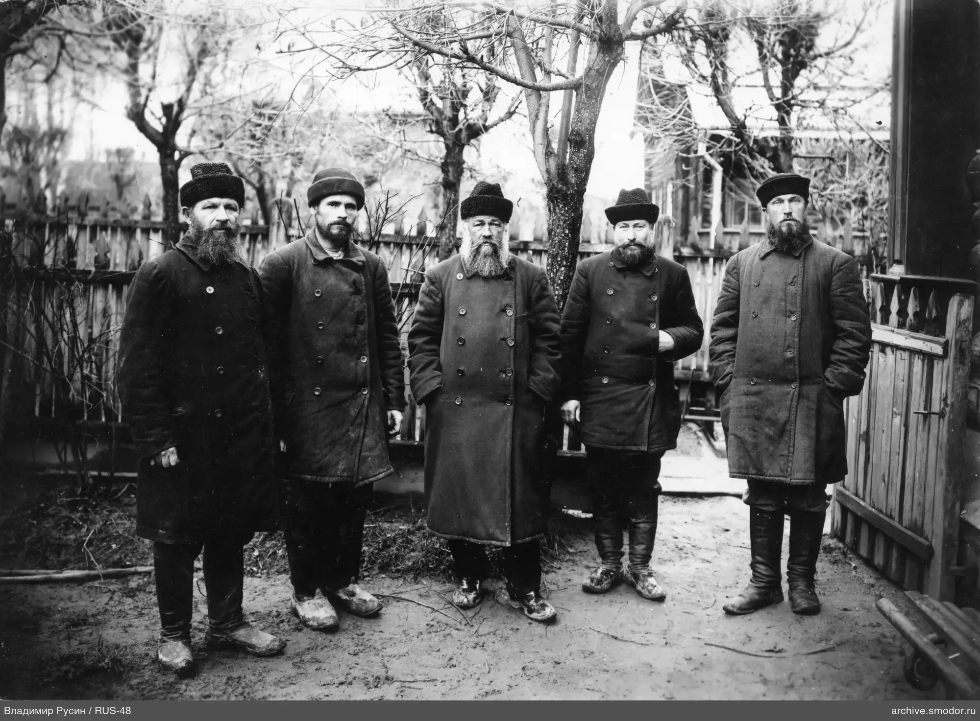 Группа мужчин в темных пальто и меховых шапках