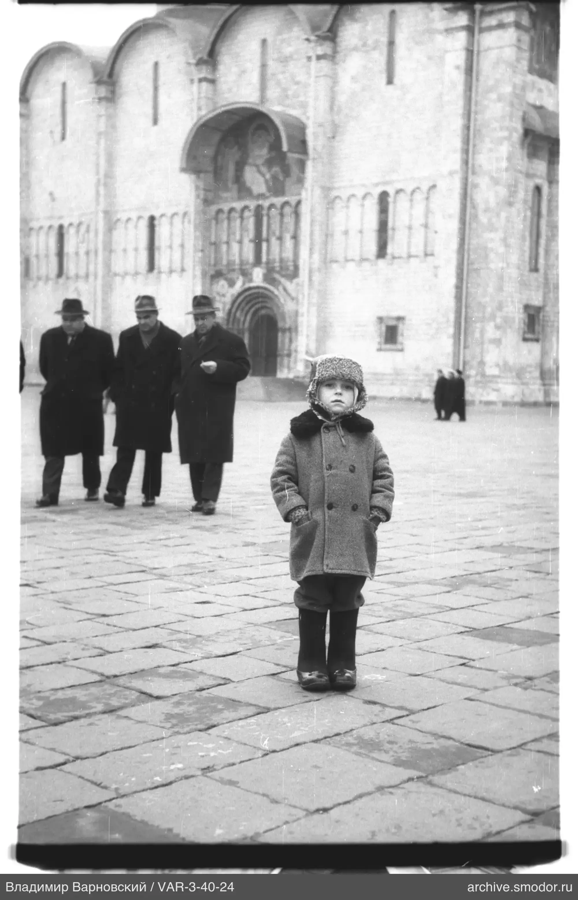 Child and men in front of stone wall