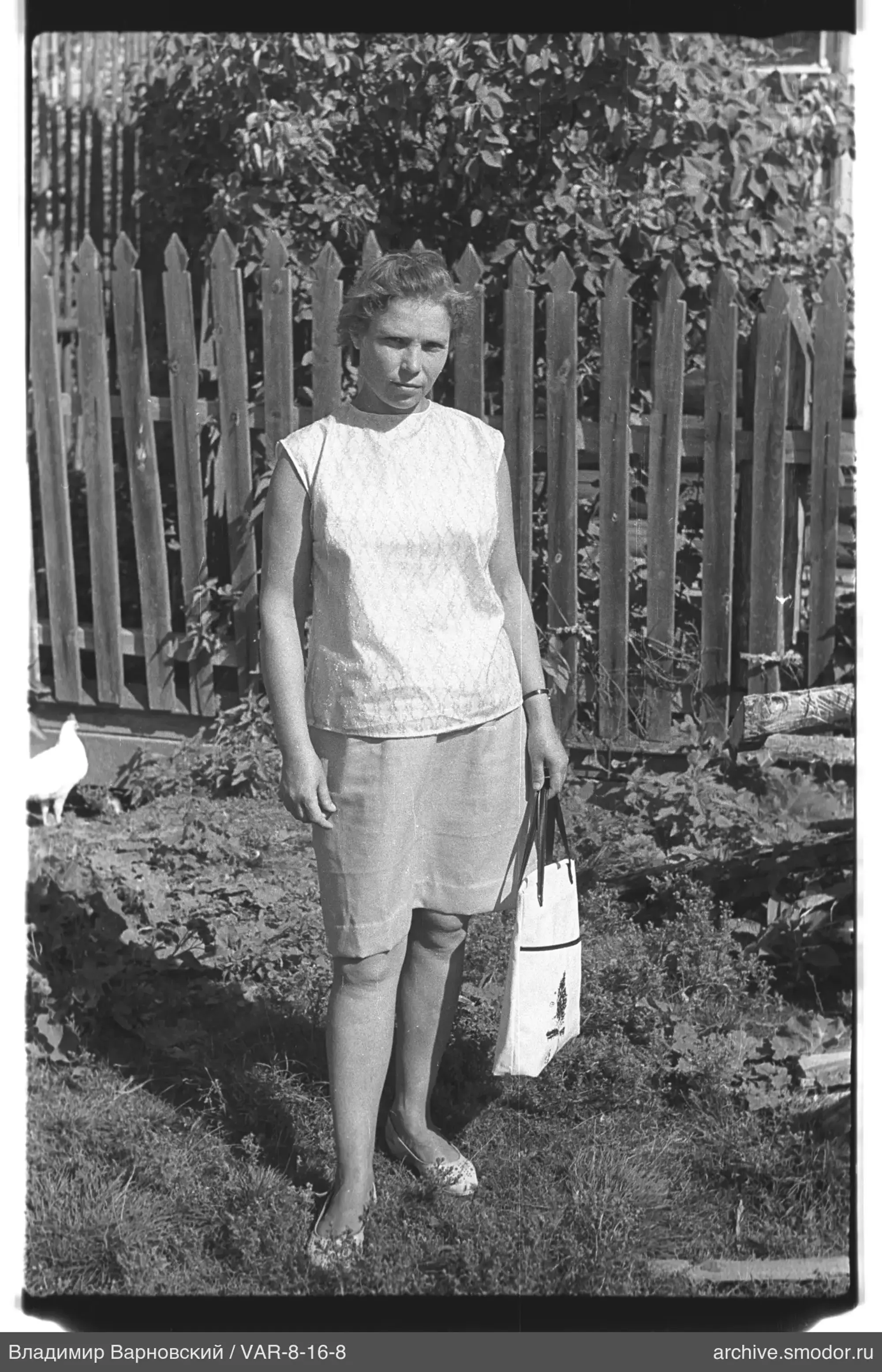 Frau mit Tasche vor Holzzaun