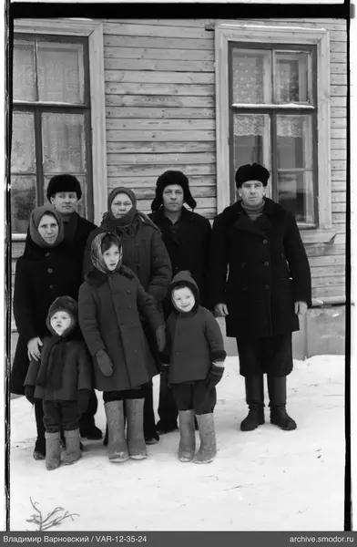 Группа людей перед деревянным домом на снегу