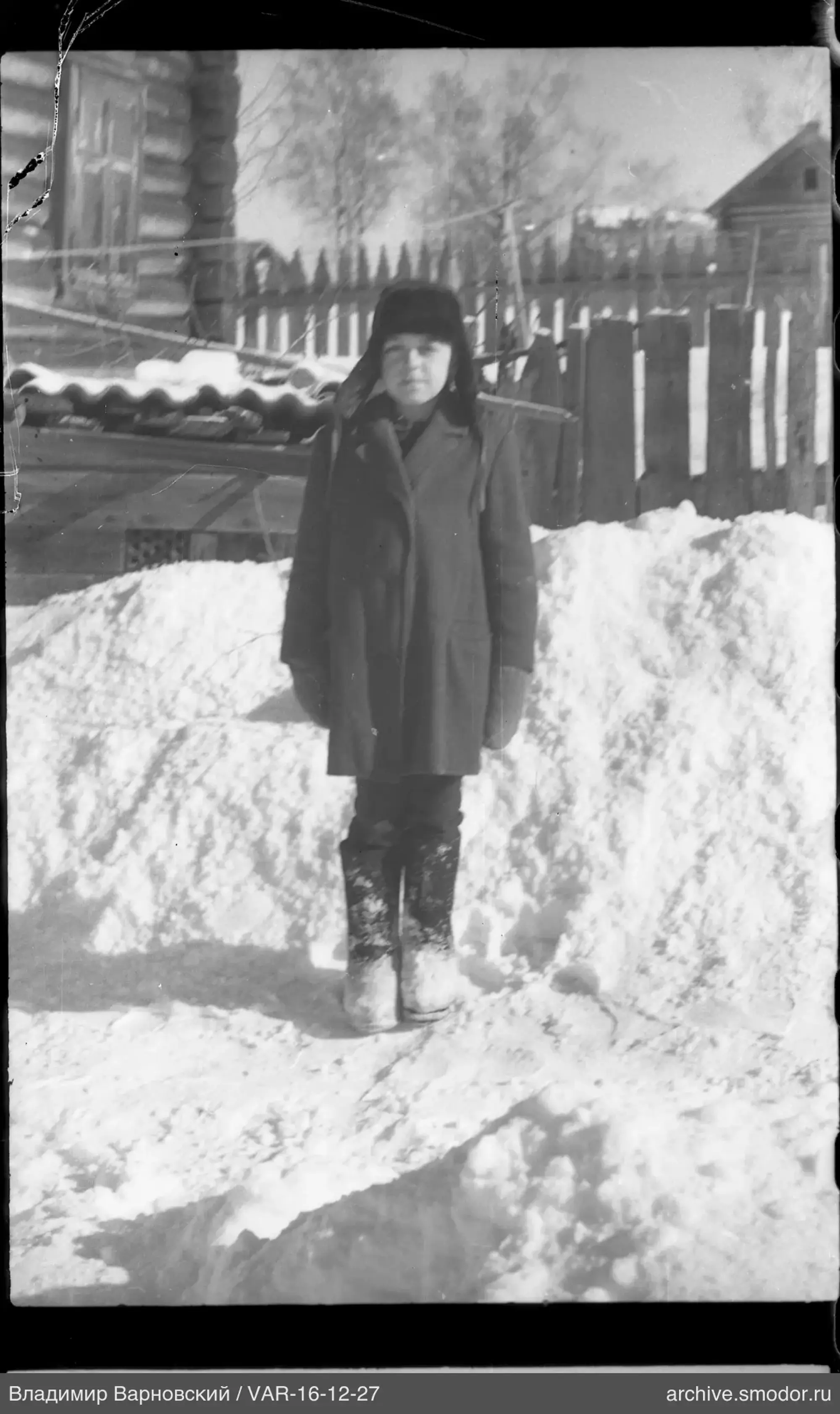 Woman standing on snow in front of house