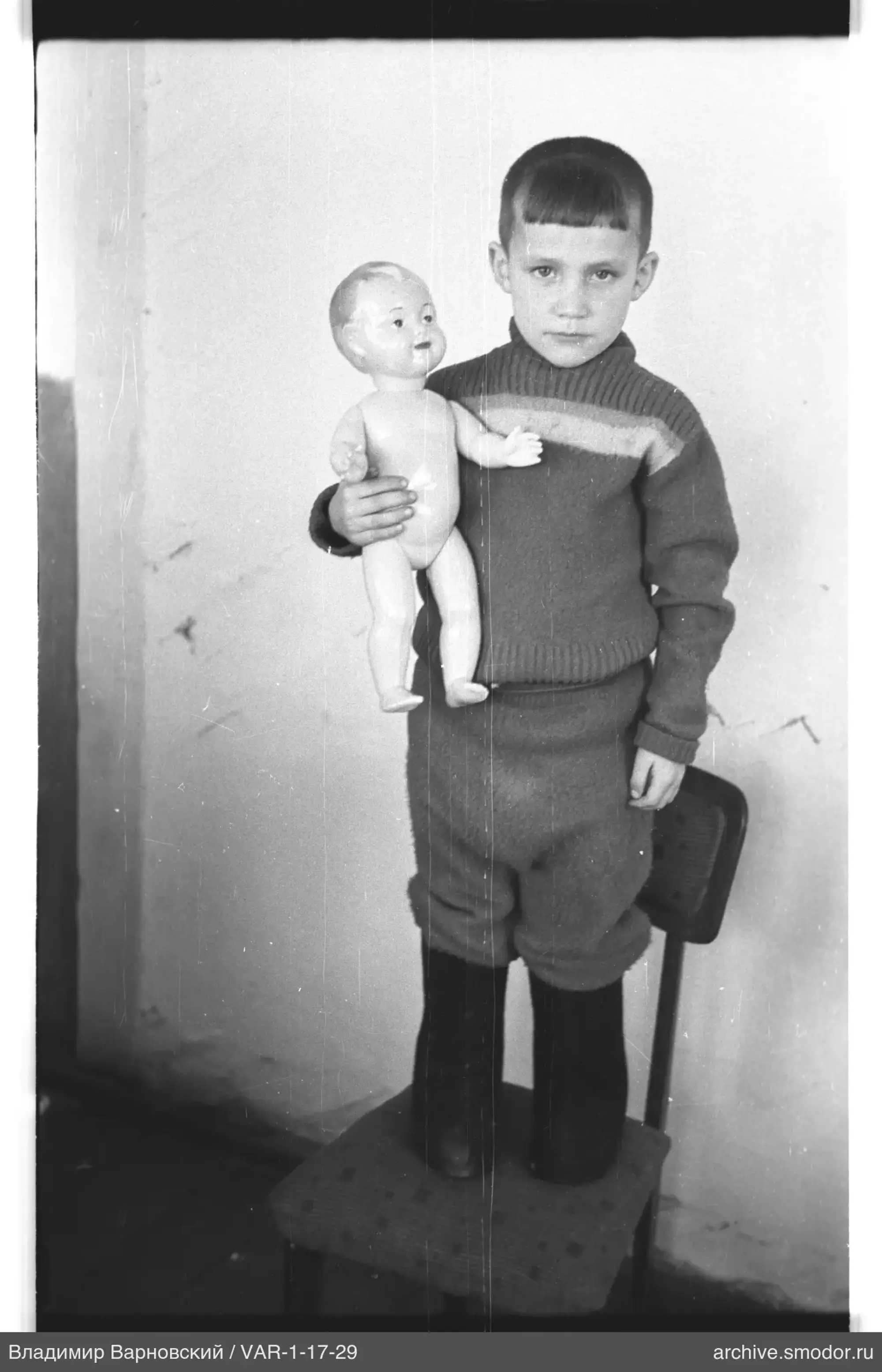 Boy holding a doll on a chair