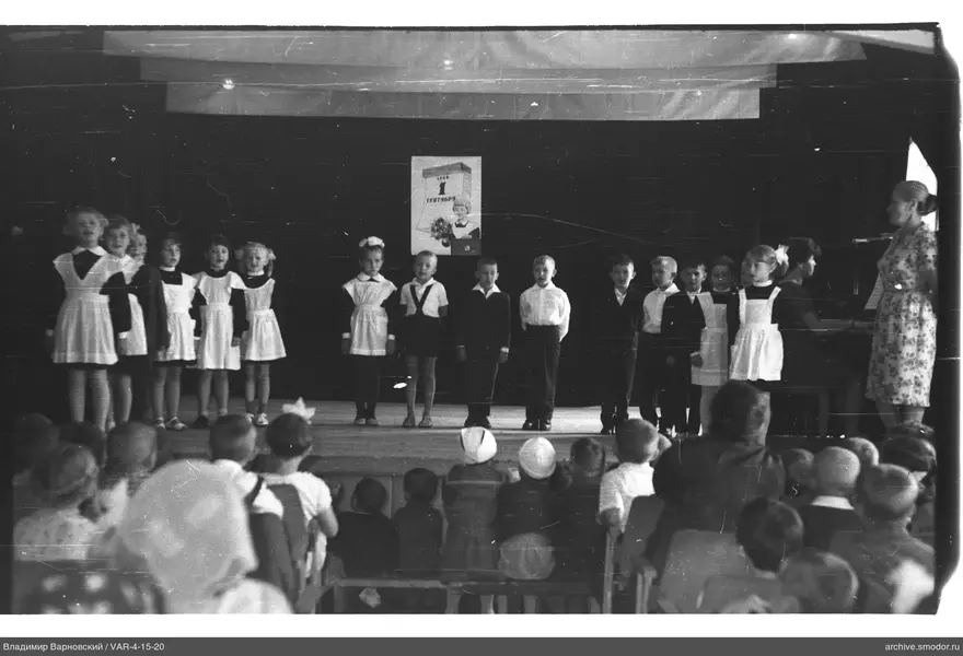 Kinder auf der Bühne mit Frau und Plakat