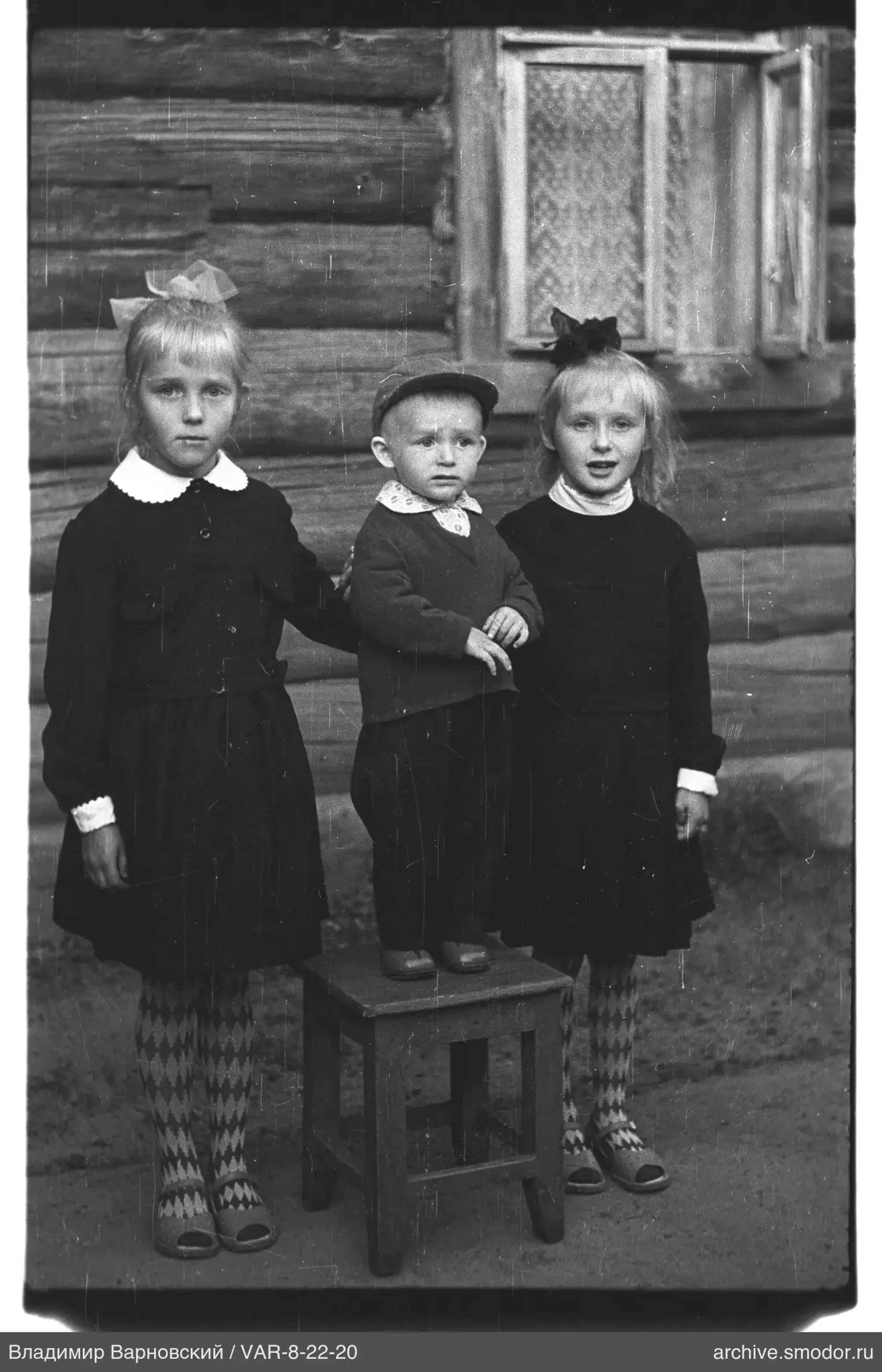 Gruppenporträt von Kindern vor Holzhaus