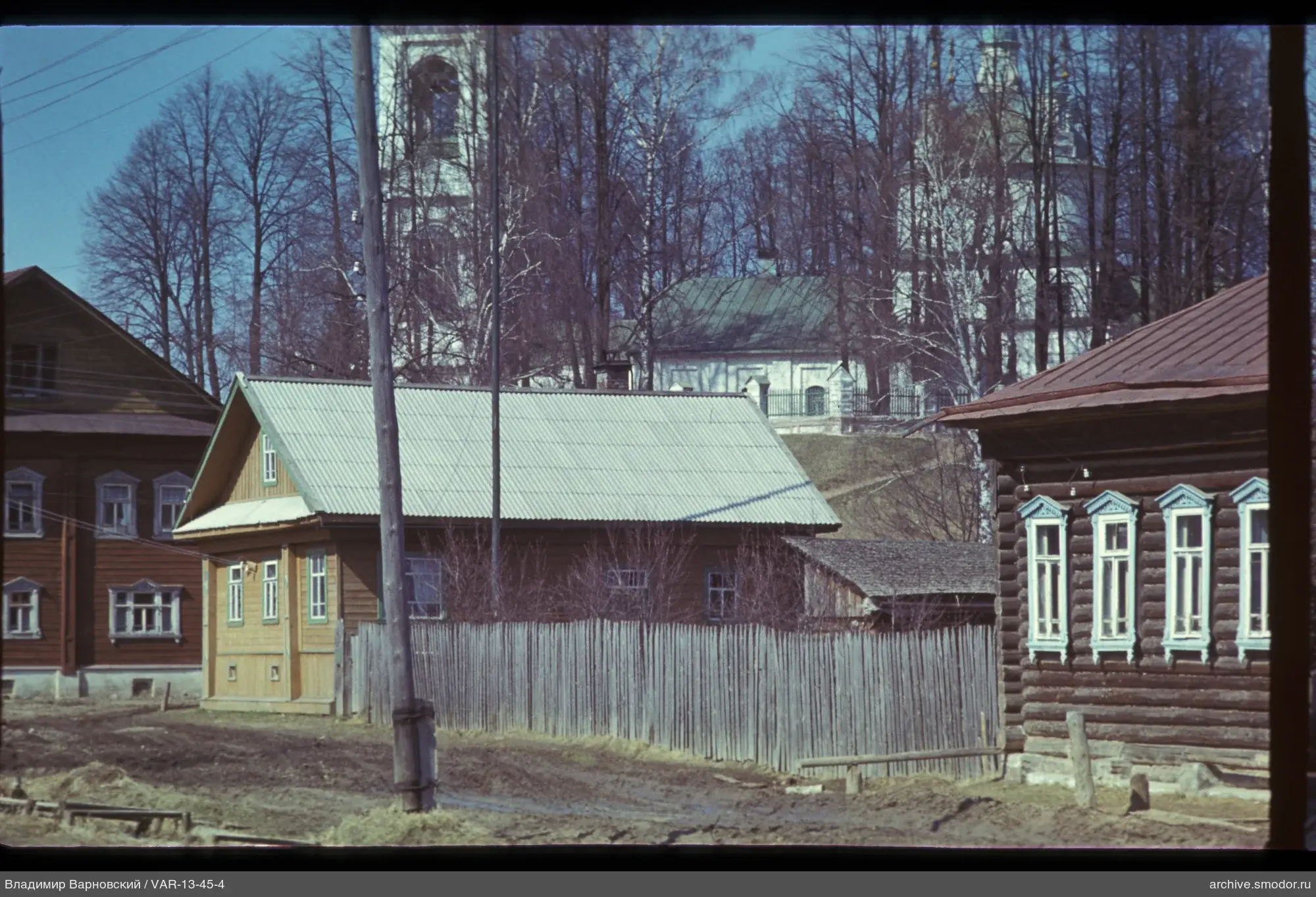 Holzhäuser und Kirche vor Bäumen