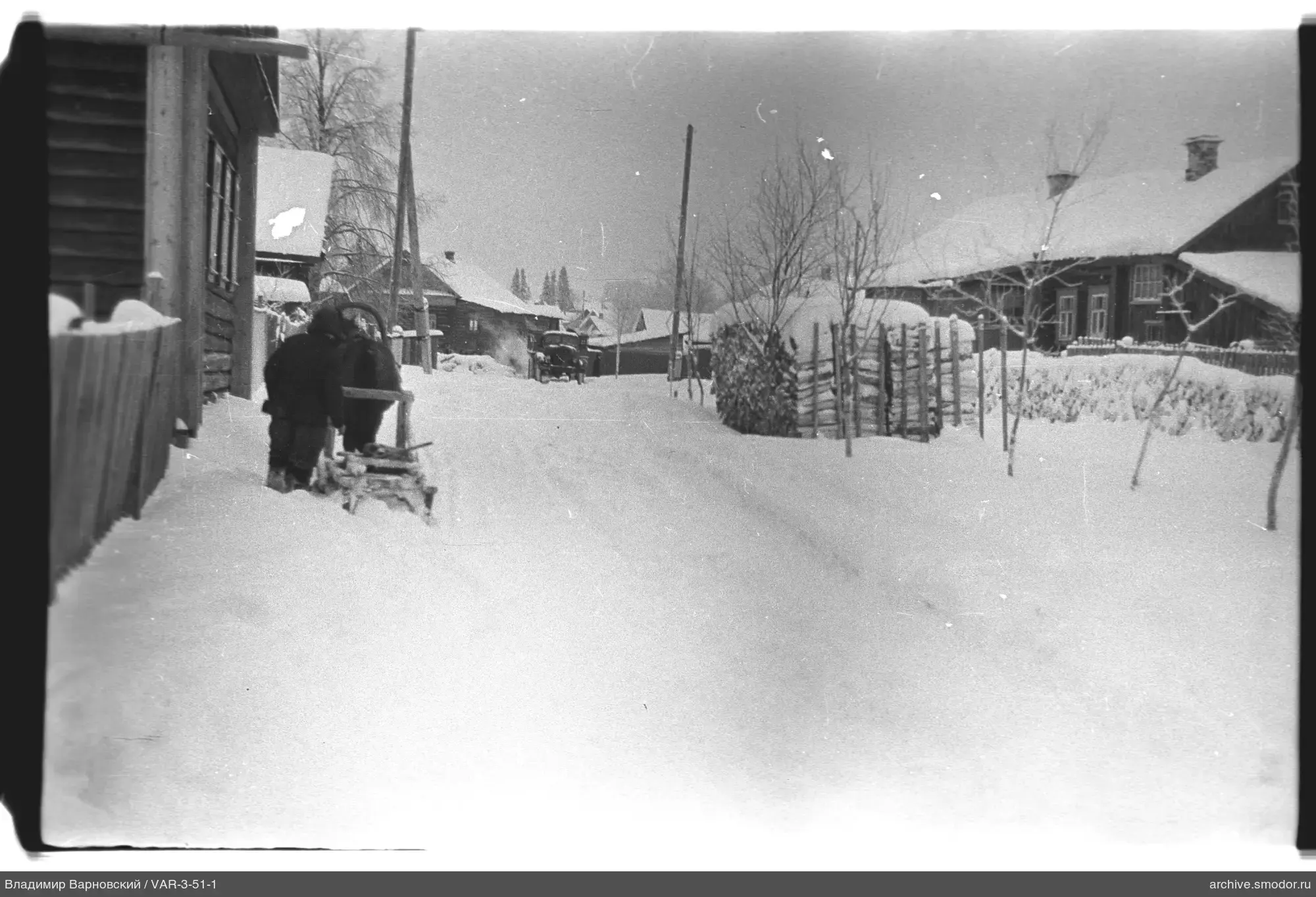Snow-covered street with wooden houses