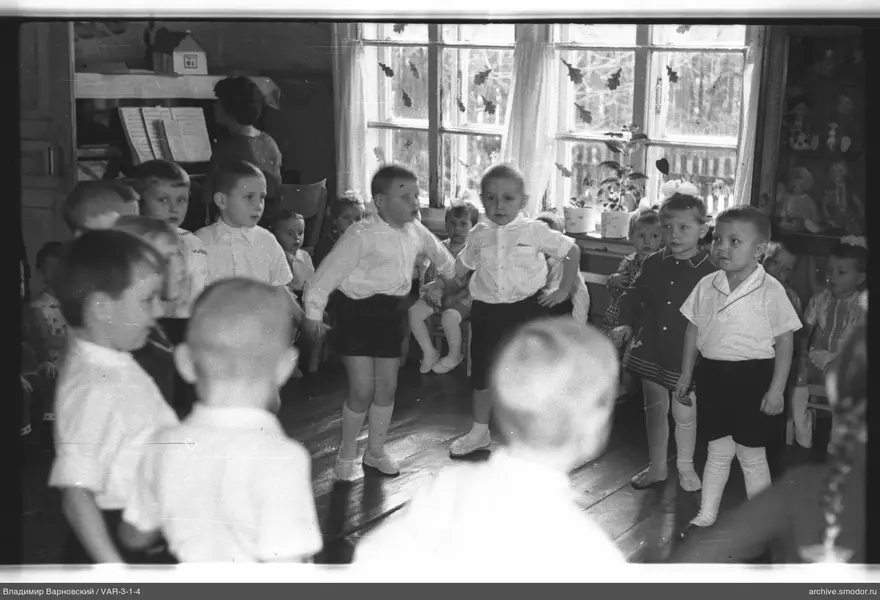 Kinder in einem Raum mit Möbeln und einer Frau