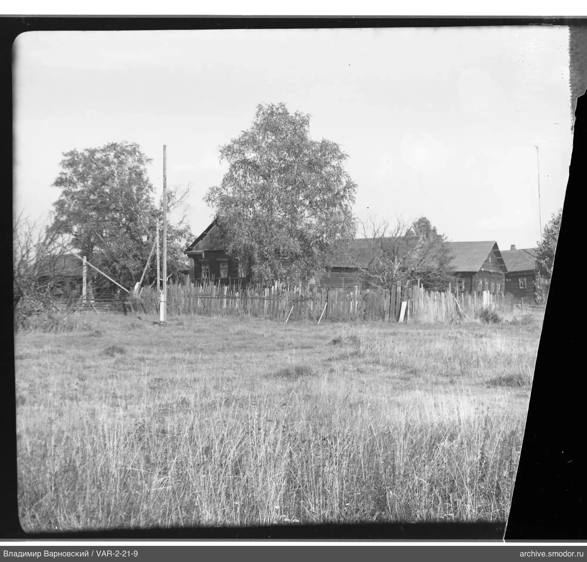 Landschaft mit Feld, Zaun und Häusern