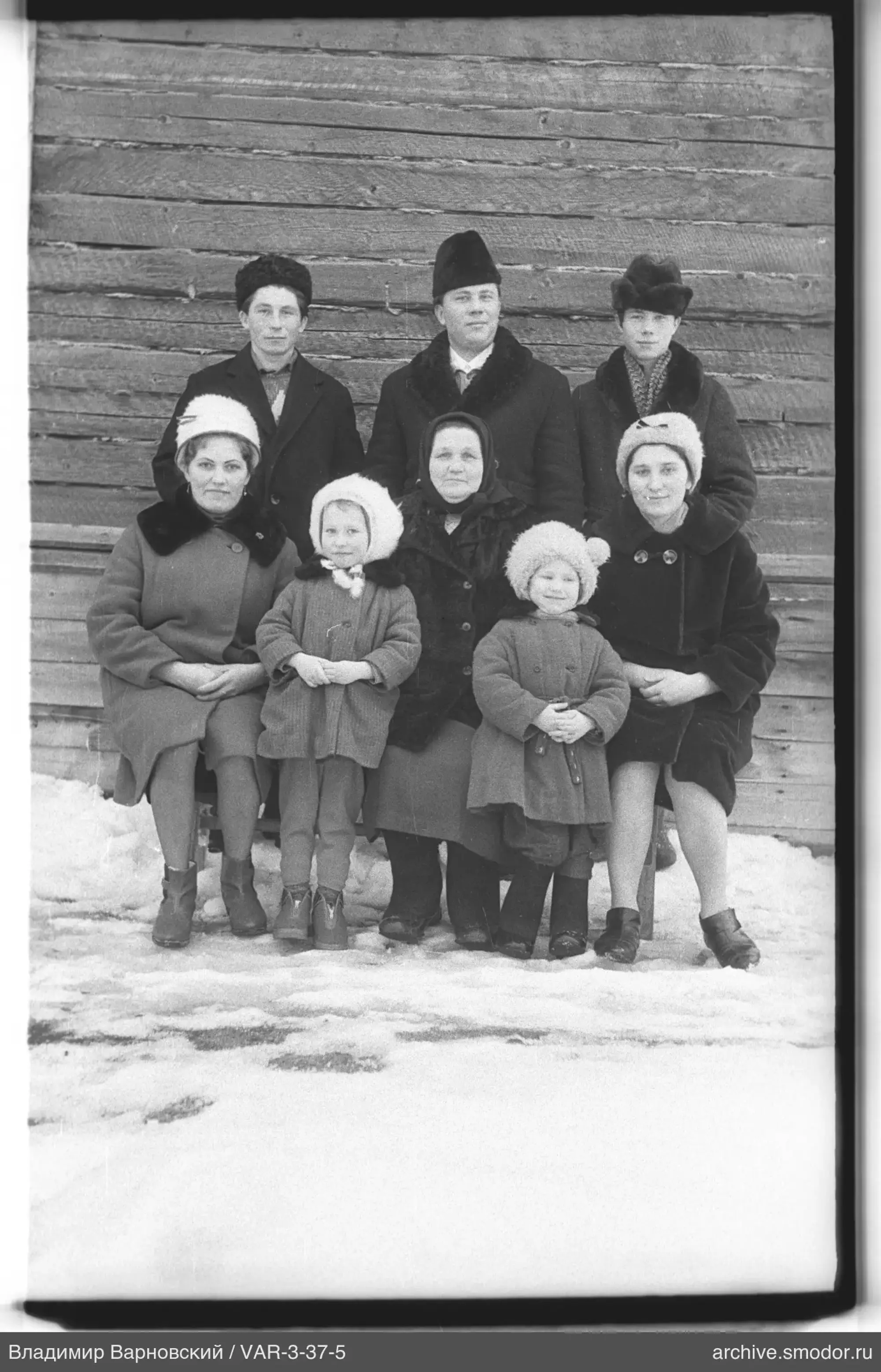 Group portrait on snow near wooden wall