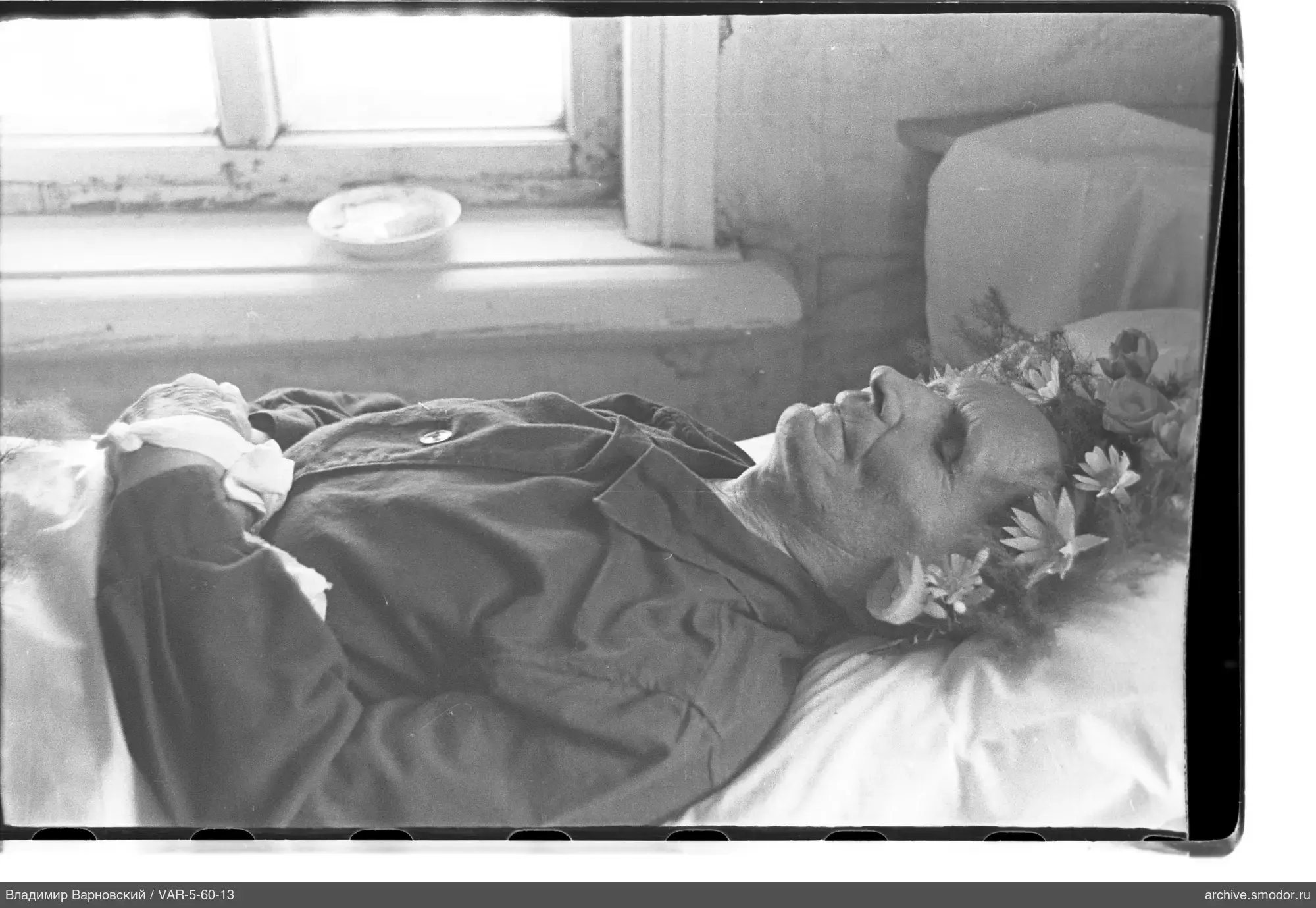 Person mit Kranz und Verband auf Bett