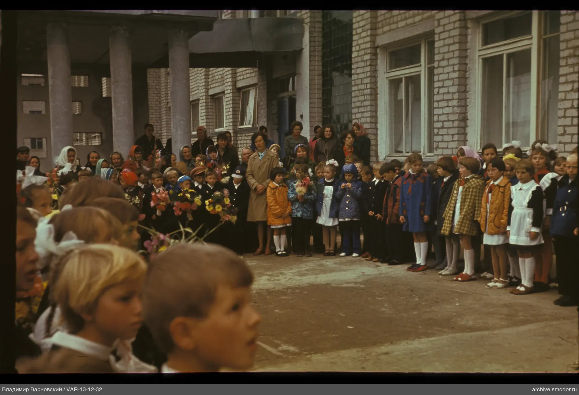 Group of children and adults near a brick building