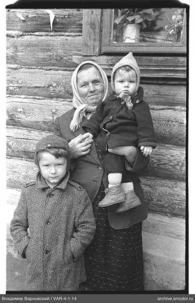 Frau mit Kindern am Holzhaus