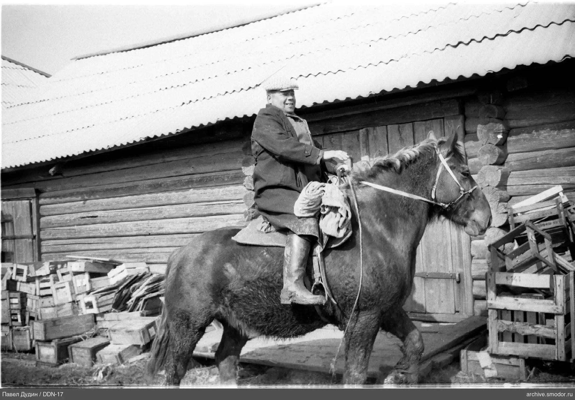 Mann auf einem Pferd neben einem Holzgebäude