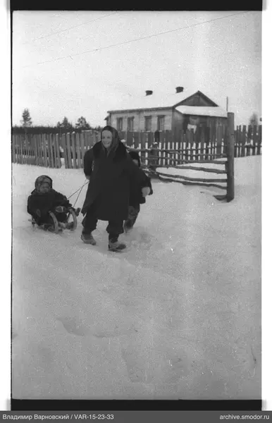 Женщина с санками и детьми на снегу