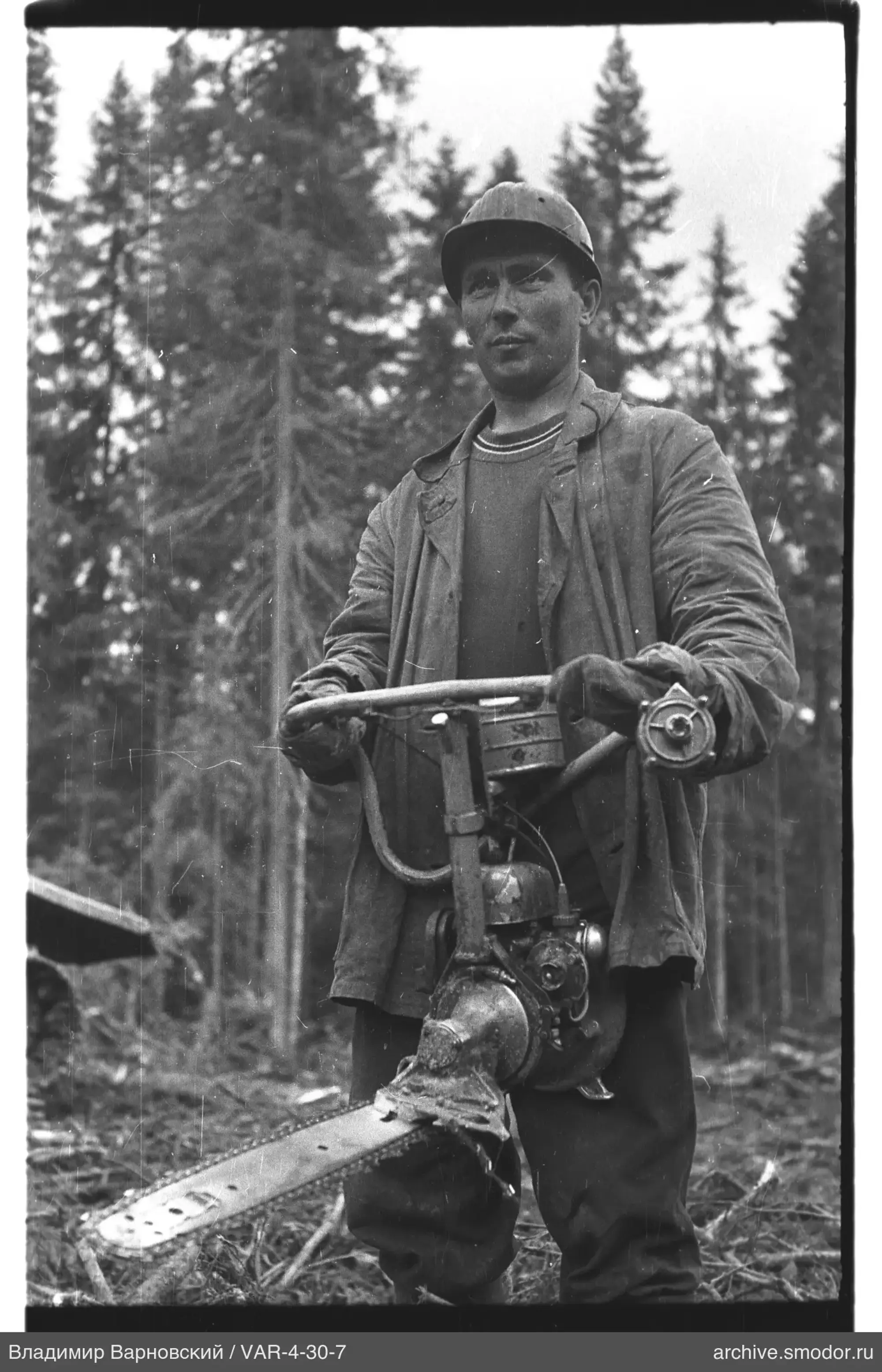 Mann mit Motorsäge vor Bäumen