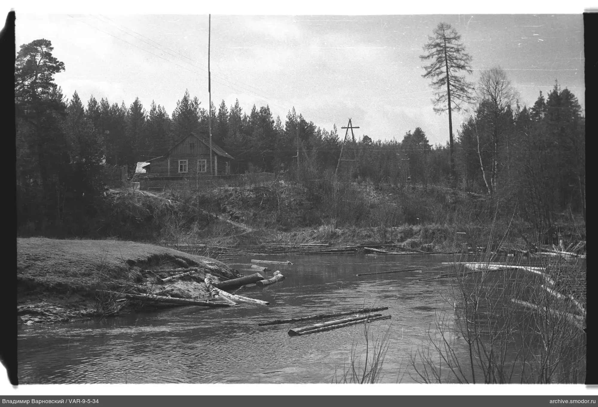 Fluss mit treibenden Baumstämmen und Holzhaus