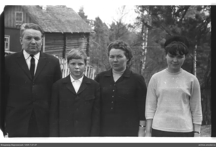 Gruppe von vier Personen vor einem Holzhaus