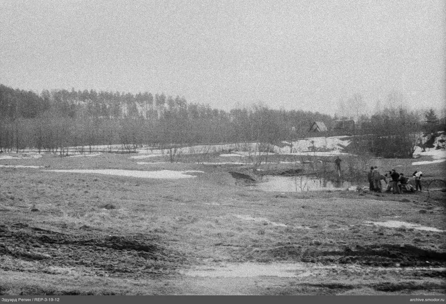Gruppe von Menschen vor Wald und Häusern