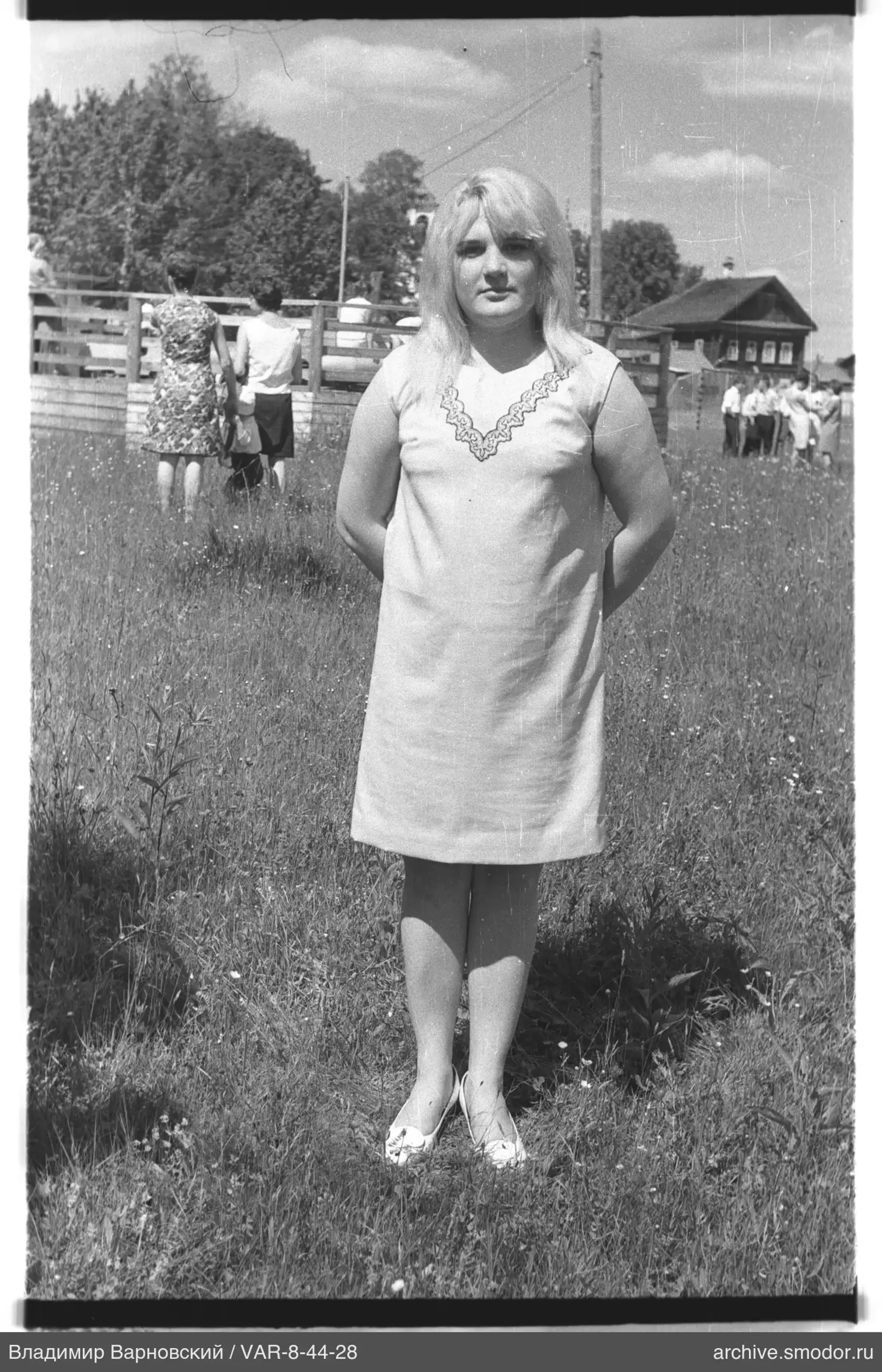 Frau in hellem Kleid auf grasbewachsenem Feld