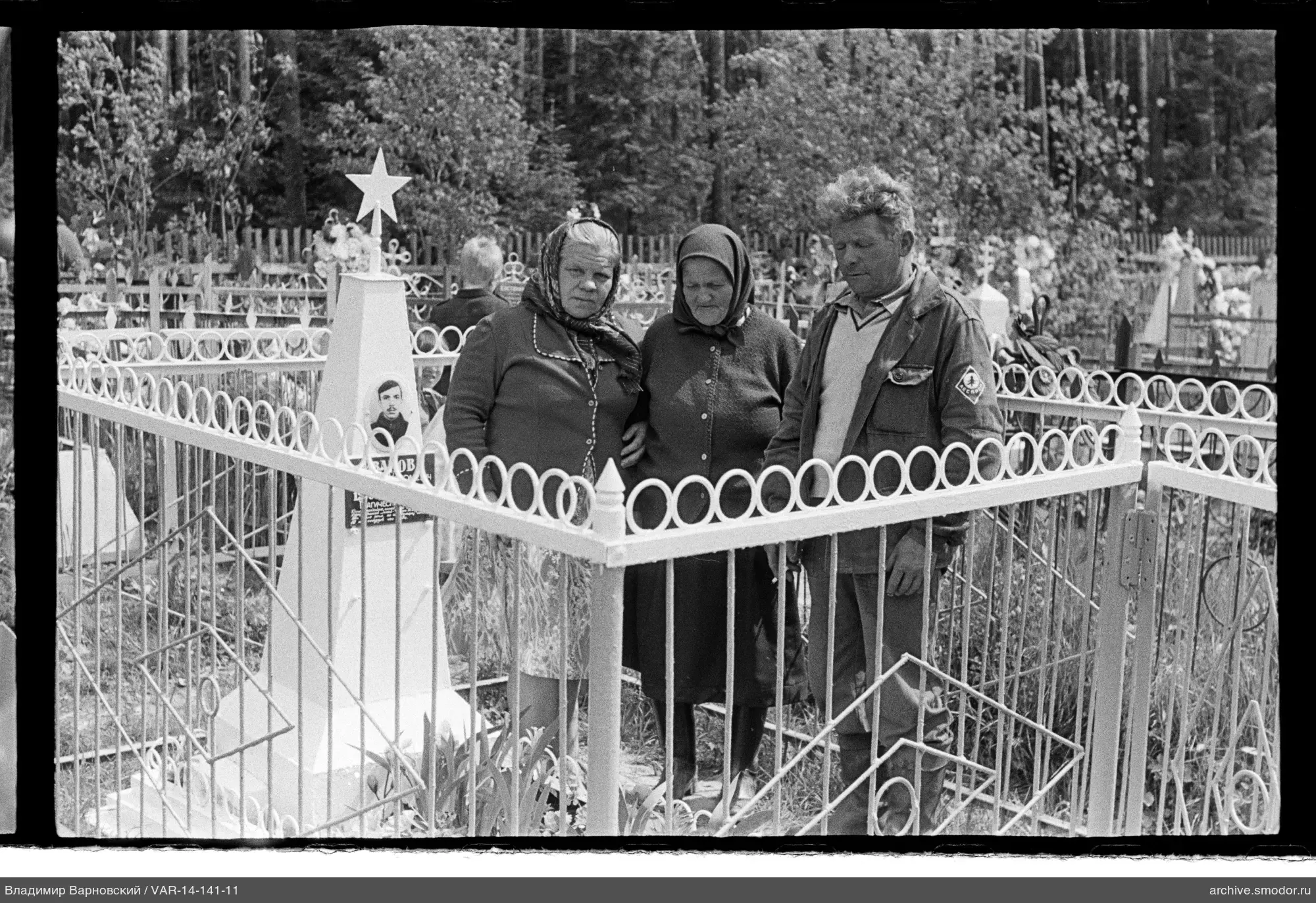Drei Personen am Grabmal auf dem Friedhof