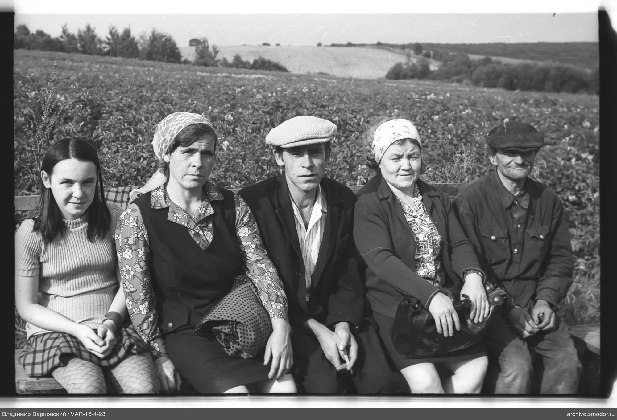 Gruppe von Menschen auf einer Bank vor einem Feld