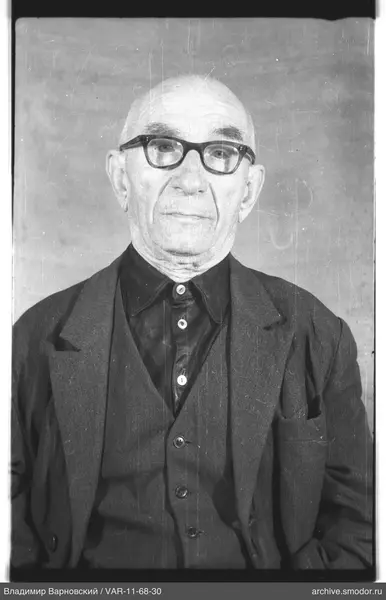 Ganzkörperporträt eines glatzköpfigen Mannes mit Brille