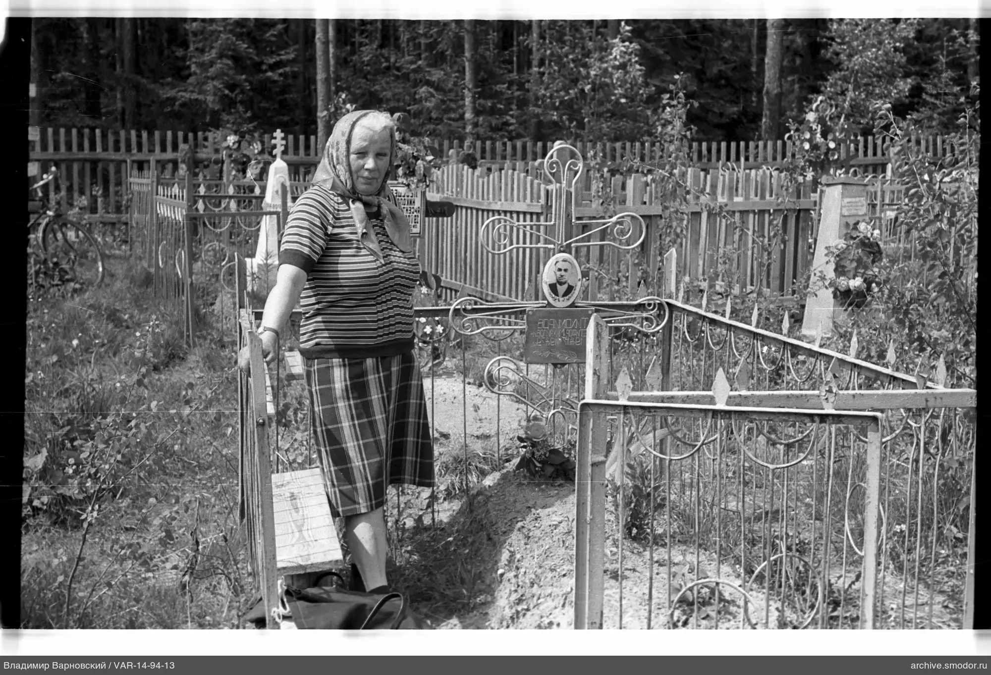 Woman at grave with man's photograph