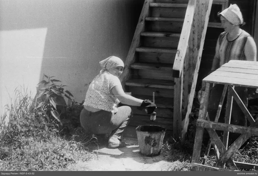 Frau mit Pinsel neben Leiter