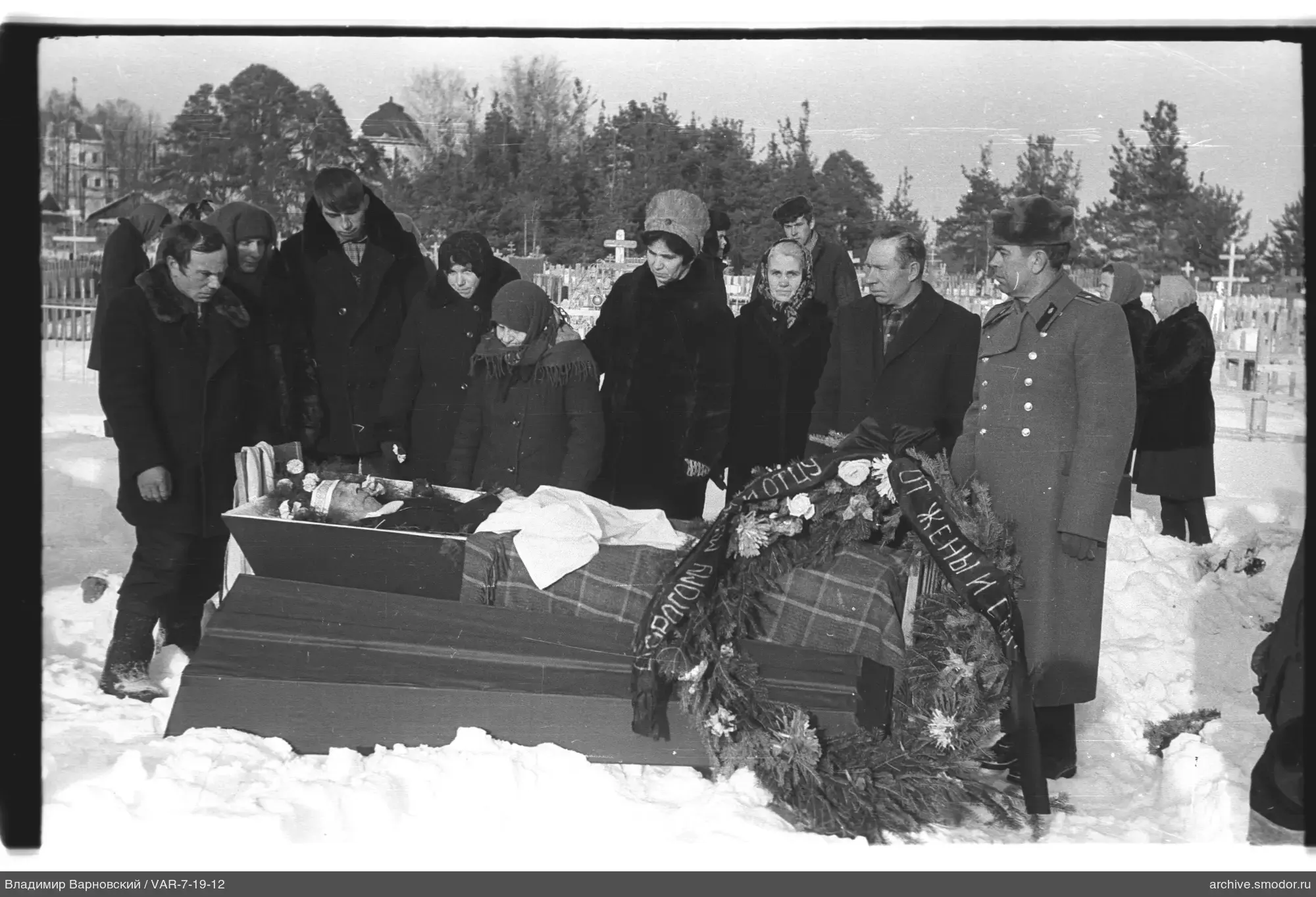 Gruppe um einen offenen Sarg auf dem Friedhof