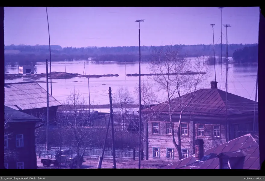 Wooden houses by the river with antenna and forest