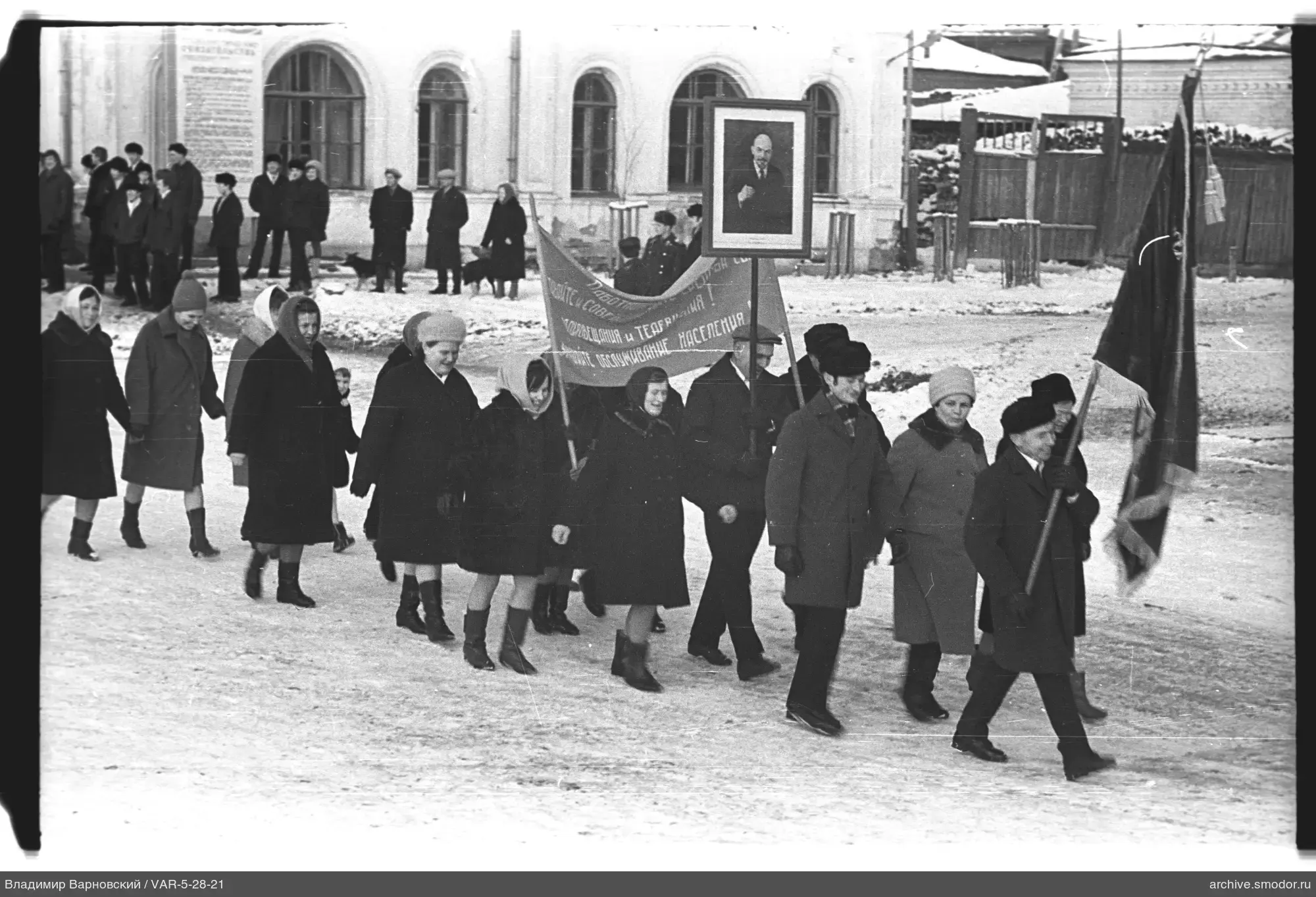 Группа людей на снежной улице с флагом и портретом Ленина
