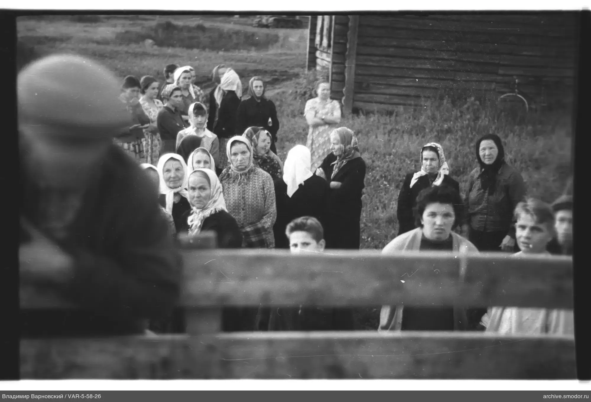 Gruppe von Frauen und Jugendlichen bei einem Holzhaus