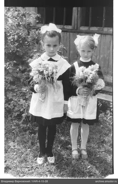Zwei Mädchen in Schuluniformen mit Blumensträußen