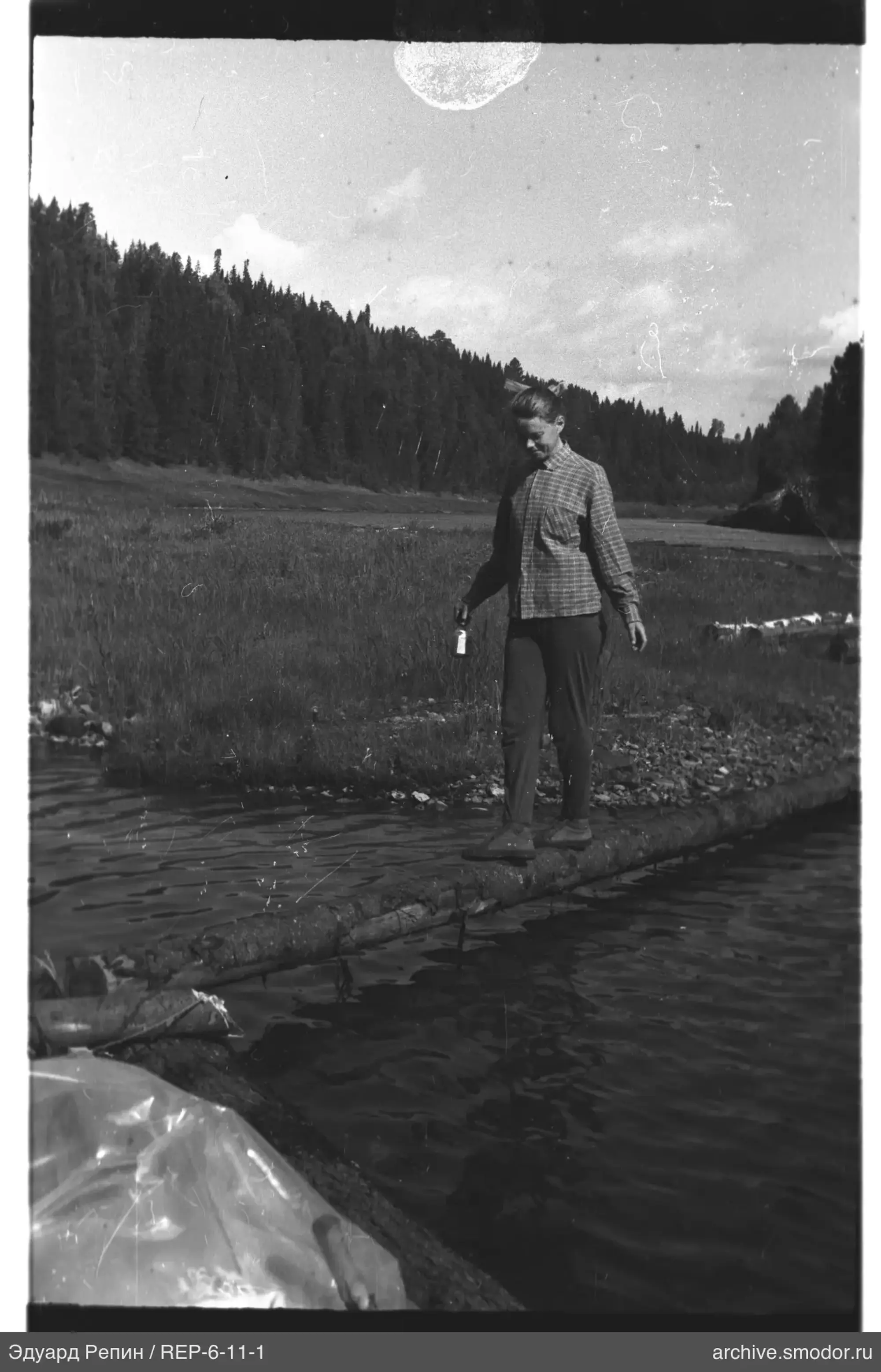 Frau auf Baumstamm über Wasser