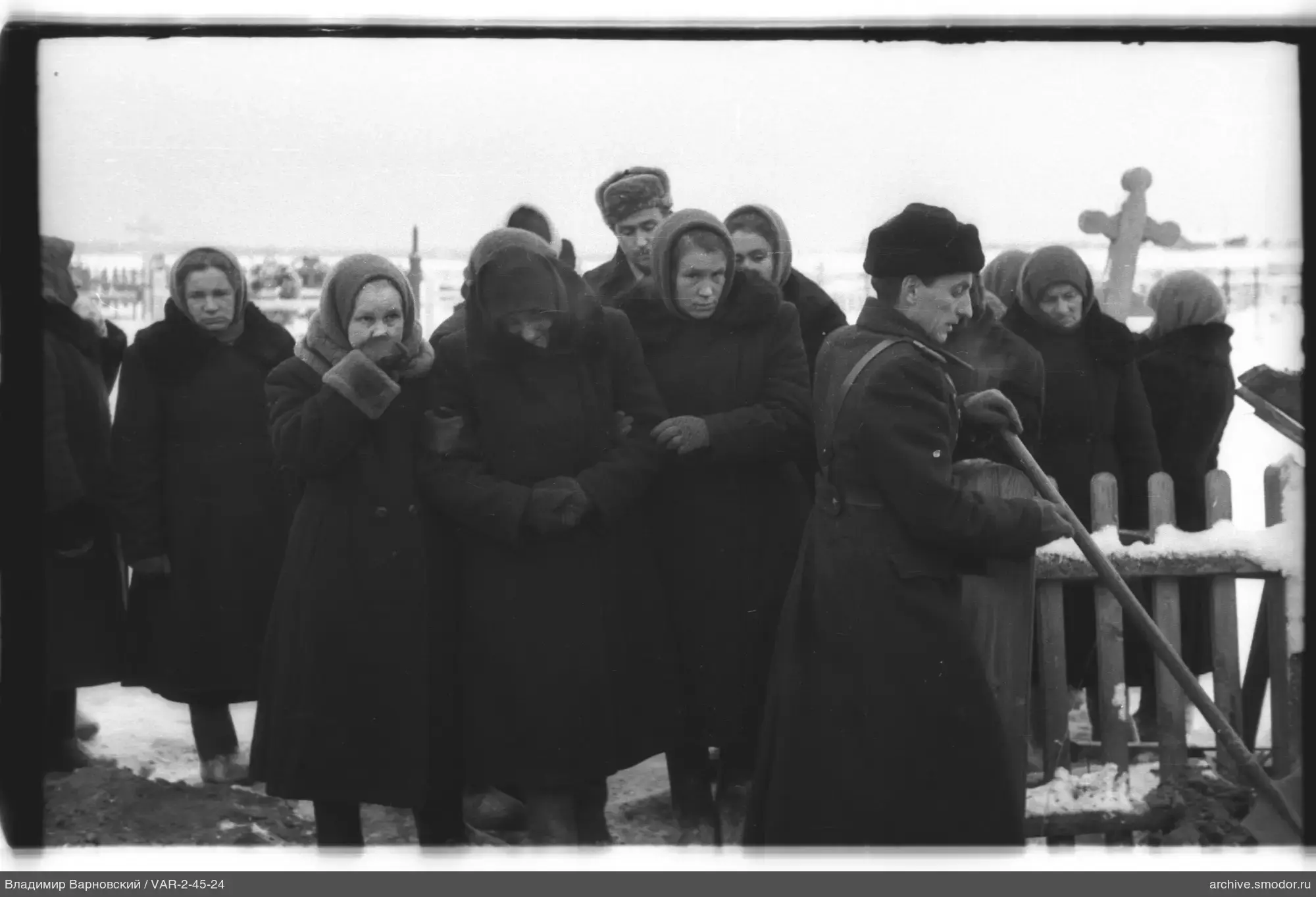 Группа людей у могильных крестов