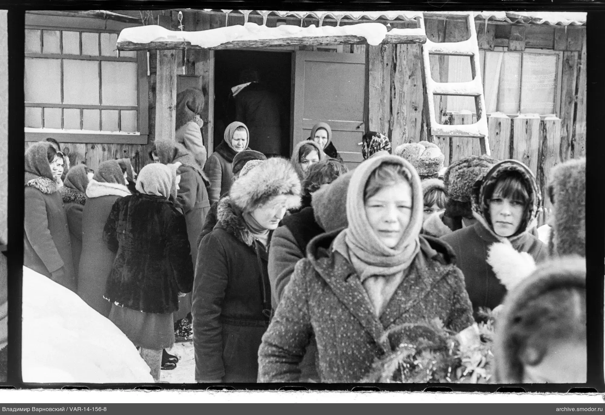 Gruppenaufnahme von Frauen bei einem Holzhaus