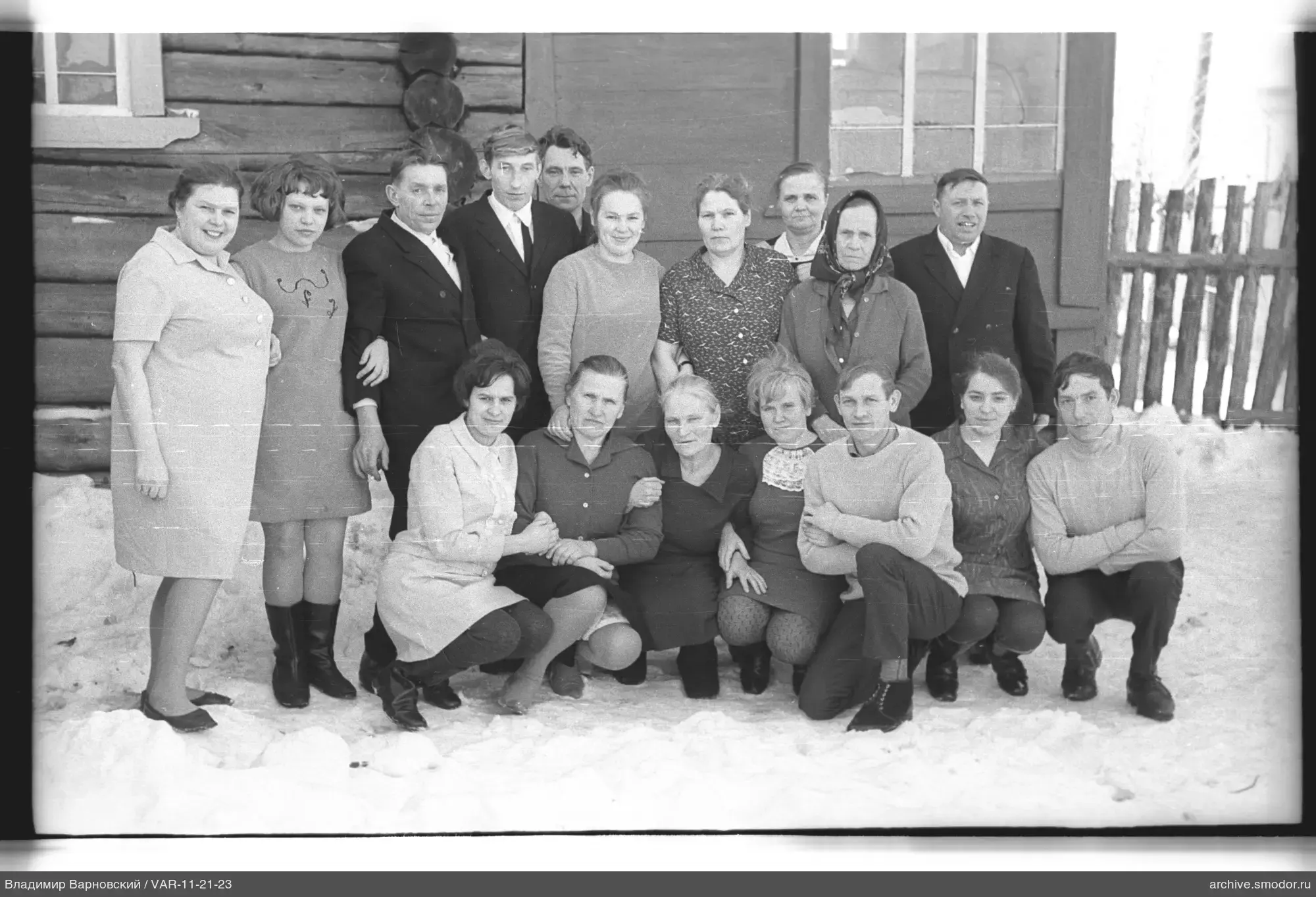 Gruppe von Menschen bei einem Holzhaus im Schnee