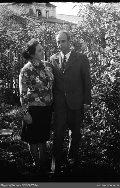 Mann und Frau vor Zaun und Bewuchs