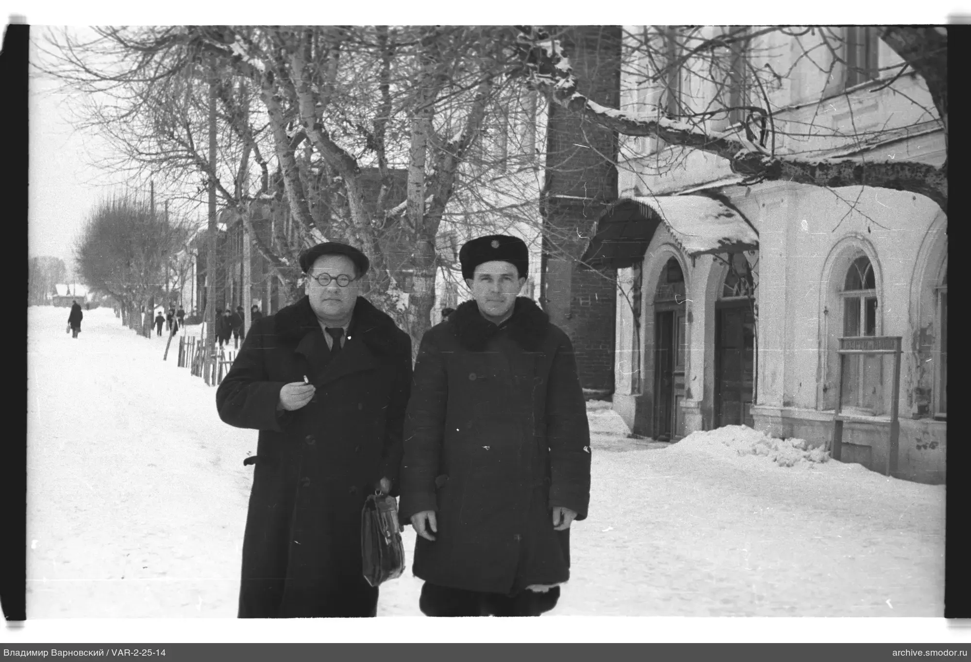 Two men on a winter street near a building
