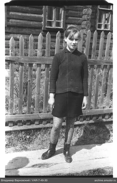 Mädchen auf Holzbrett vor Haus