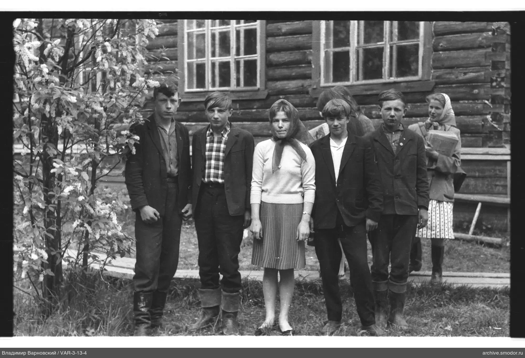 Gruppe von Jugendlichen und Frau vor einem Holzhaus