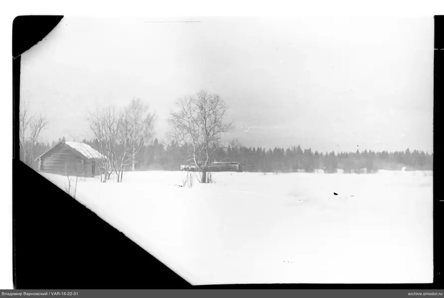 Holzhütte vor verschneitem Feld