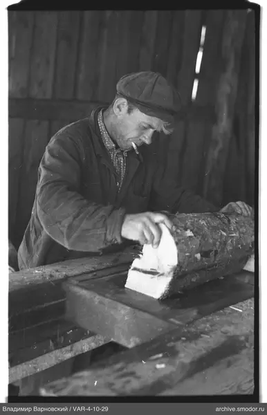 Man with woodworking tool by log