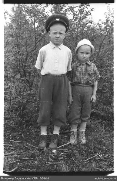 Zwei Jungen vor Büschen