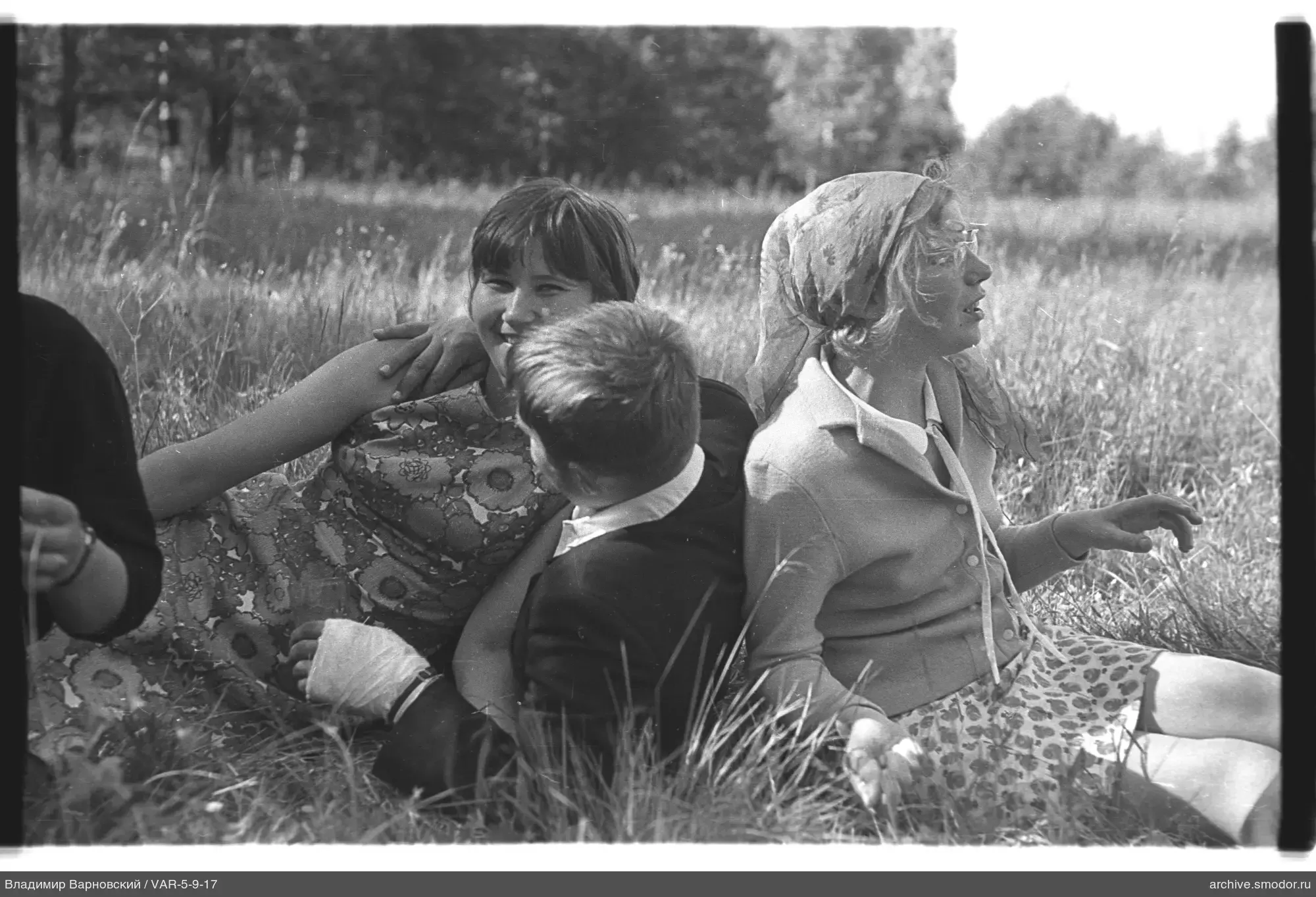 Drei junge Menschen sitzen auf dem Gras im Feld