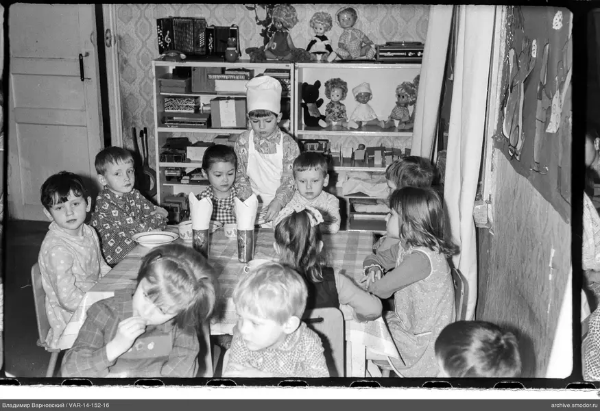 Kinder am Tisch mit Jungen im Kochhut