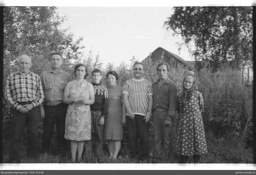 Gruppe von Menschen vor Haus und Büschen