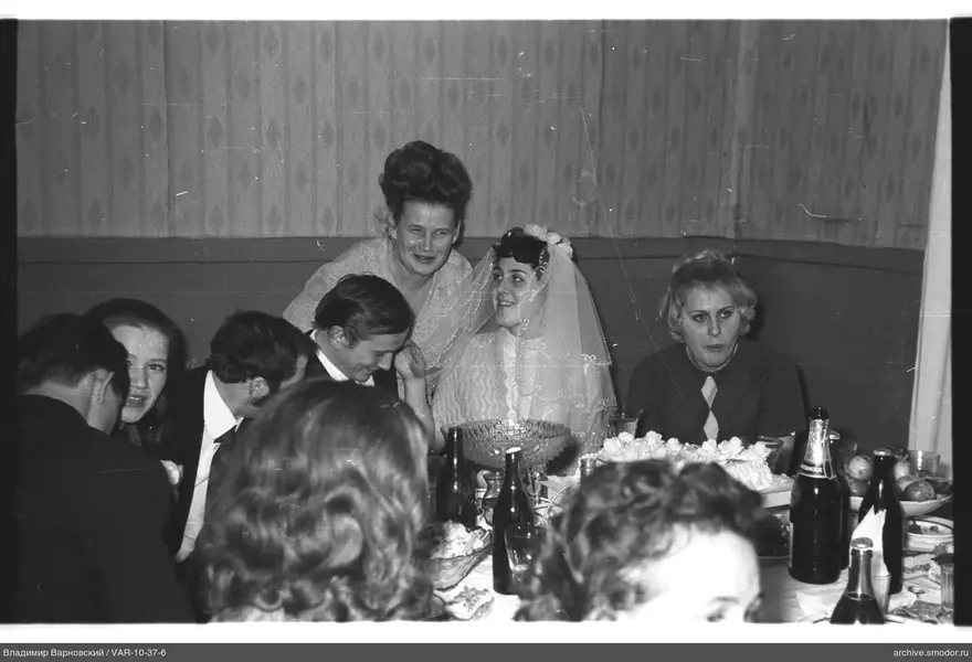 Woman in wedding dress with guests at table